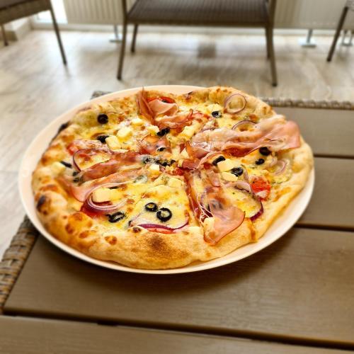 a pizza sitting on a plate on a table at MiklósGrill - Kunszentmiklósi Étterem és Panzió in Kunszentmiklós