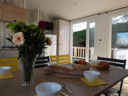 Una mesa de madera con un jarrón de flores encima. en Mobilhome 4 chambres 8 places, en Erquy