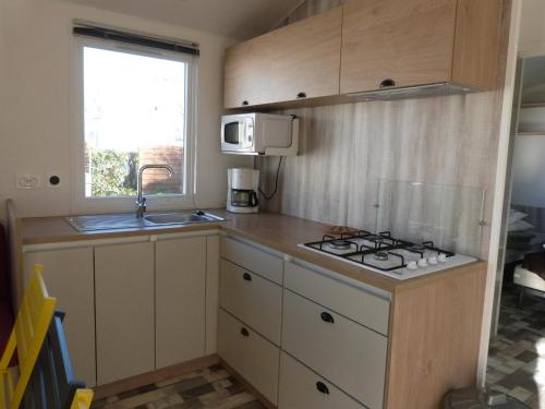Una pequeña cocina con estufa y fregadero. en Mobilhome 4 chambres 8 places, en Erquy