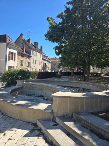 a set of concrete steps with a tree and buildings at Au cœur du vieux village in Chenôve