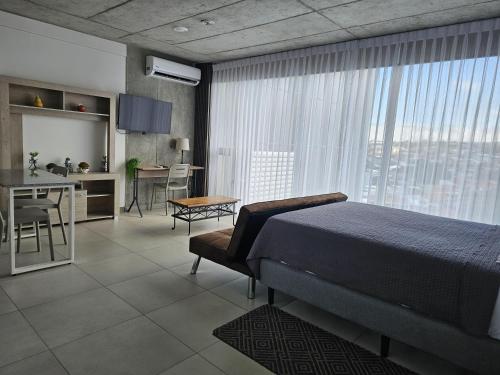 a bedroom with a bed and a table and a kitchen at Urban Breeze iFreses, 10th floor! AC, TV and Pool in Guayabos