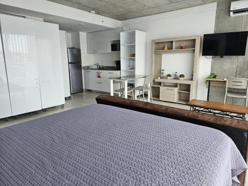 a bedroom with a bed and a table and a kitchen at Urban Breeze iFreses, 10th floor! AC, TV and Pool in Guayabos