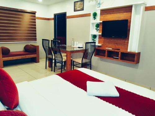 a bedroom with a bed and a table and a tv at The Rosetta Castle in Kalpetta