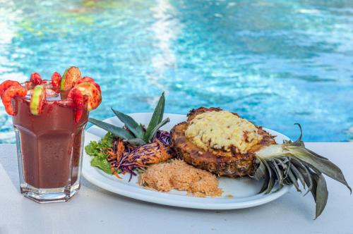 a plate of food and a drink next to a pool at Hotel Puente Nacional & Spa in Puente Nacional