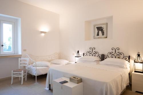 a white bedroom with a bed and a chair at Masseria Montelauro in Otranto