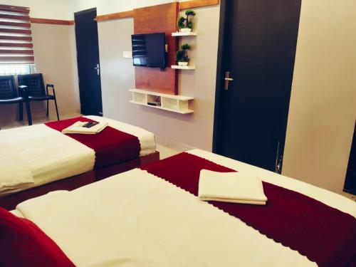 a hotel room with two beds and a tv at The Rosetta Castle in Kalpetta