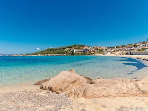 a large rock on a sandy beach with the ocean at Villa Tre Monti - Vista mare 8 posti letto- Baja Sardinia in Baja Sardinia
