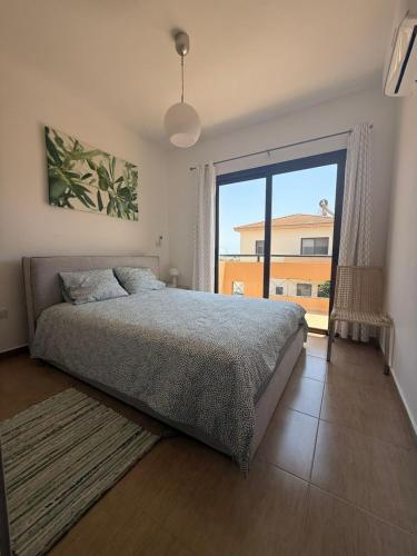 a bedroom with a bed and a large window at Dene Hollow kapparis in Paralimni