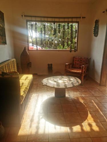 a living room with a table and chairs and a window at Bungalow accés direct plage privée "Plage tropicale Chez Jack et Régine" in Grand-Bassam