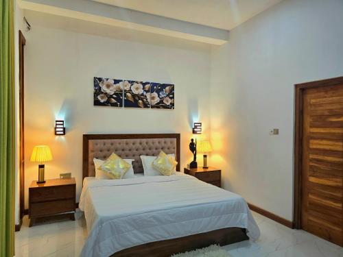 a bedroom with a large bed and two night stands at Aurora White Bungalow Kandy in Kandy