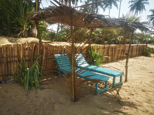 a blue chair sitting under an umbrella on the beach at Bungalow accés direct plage privée "Plage tropicale Chez Jack et Régine" in Grand-Bassam