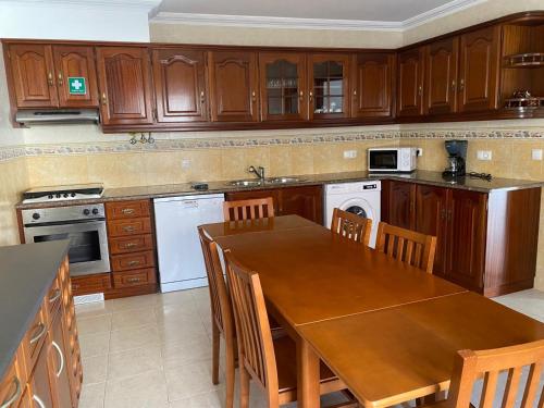 Una cocina con gabinetes de madera y una mesa de madera. en SwordFish Charming Retreat, en Peniche