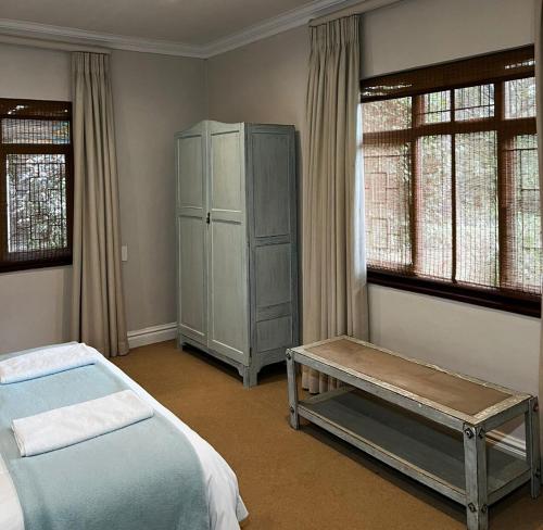 a bedroom with a bed and a cabinet and windows at Aviemore Farmhouse in Nottingham Road