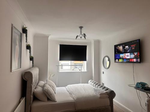 a white bedroom with a bed and a window at Enjoy city living in this one-bedroom flat, complete with a balcony and secure parking in Birmingham city center in Birmingham