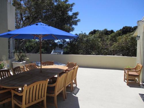 a wooden table with a blue umbrella on a patio at Saint Ann's Court in Laguna Beach