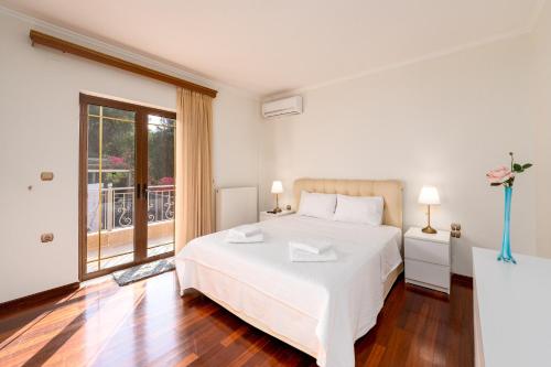 a white bedroom with a bed and a balcony at Georgias paradise villa and Garden in Kamárai