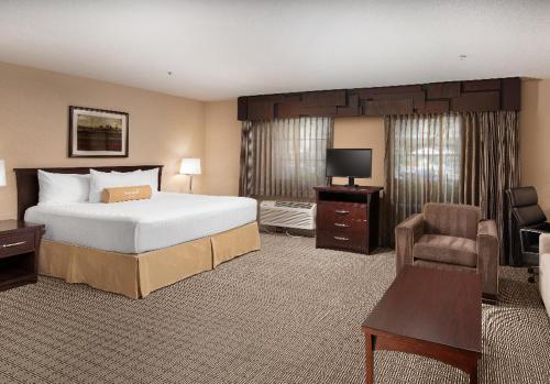 a hotel room with a large bed and a chair at Tuscany Suites & Casino in Las Vegas