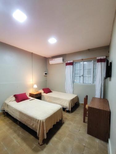 a bedroom with two beds and a table and a window at Cómo en casa, cerca de todo, amplio 100m2 in San Miguel de Tucumán