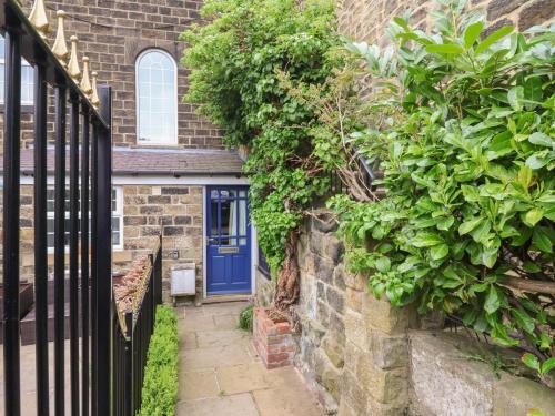 a blue door on a brick house with plants at Baht'at Cottage in Ilkley