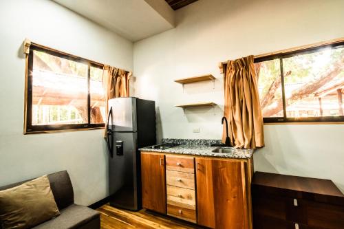 a small kitchen with a refrigerator and a counter at Rusteak Living Retreat in natural and peaceful setting in Canafistula in Cañafístula