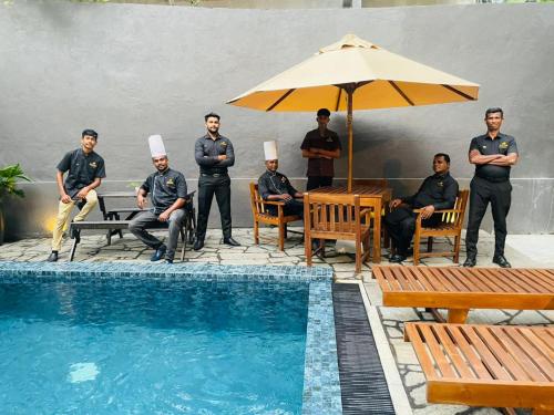 a group of men in uniform standing next to a swimming pool at Villa Mossa Ambalangoda Boutique villa in Ambalangoda