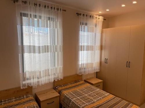 a bedroom with two beds and two windows at Everbright Seaside Serenity in Himare