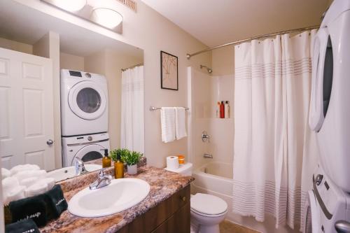a bathroom with a sink and a washing machine at Cozy & Stylish Laneway suite in Regina
