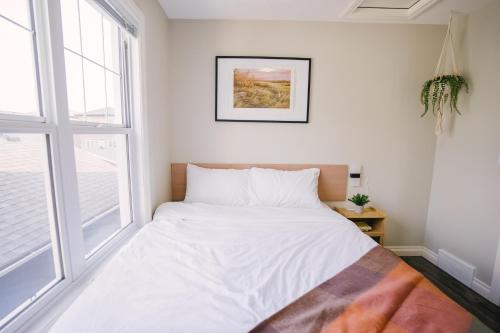a white bed in a room with a window at Cozy & Stylish Laneway suite in Regina