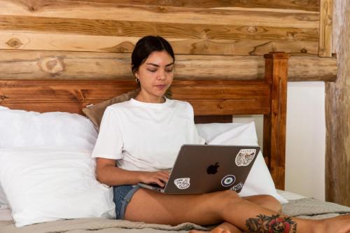 a woman sitting on a bed with a laptop at Rusteak Living Retreat in natural and peaceful setting in Canafistula in Cañafístula