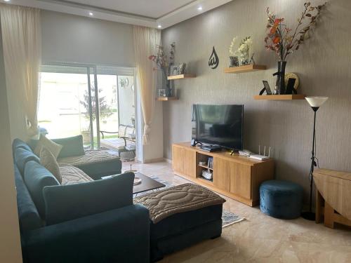 a living room with a couch and a television at Résidence CasaBay avec piscine et en bord de mer -Sidi Rahal Plage in Sidi Rahal