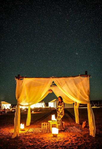 a person standing under a tent at night at Sahara Soul luxury Camp in Merzouga