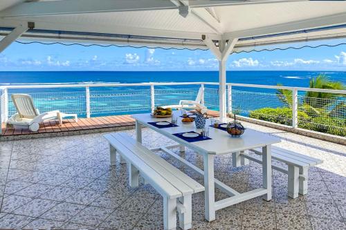a white table and benches on a balcony with the ocean at Villa Pointe Cap Est in Le François