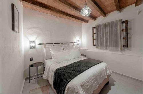 a white bedroom with a bed and a window at Casa Paulina in Guanajuato