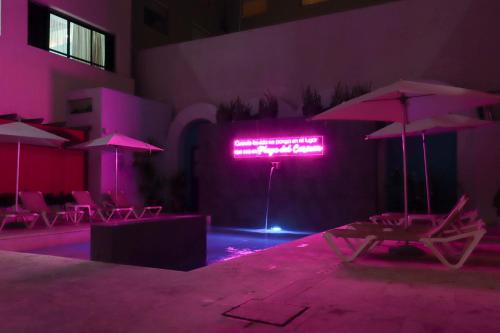 a neon sign in a building with chairs and umbrellas at Hotel MX portal maya in Playa del Carmen