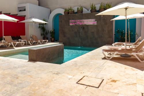 a swimming pool with lounge chairs and umbrellas at Hotel MX portal maya in Playa del Carmen
