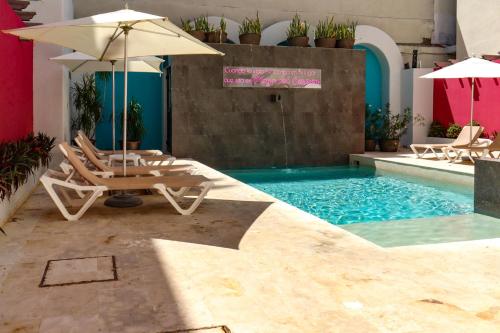 a pool with two lounge chairs and an umbrella at Hotel MX portal maya in Playa del Carmen