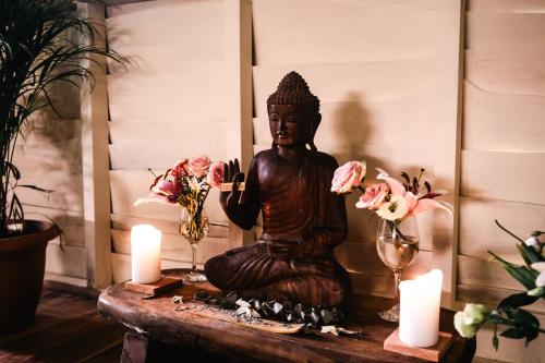 a statue sitting on a table with candles and flowers at Rusteak Living Retreat in natural and peaceful setting in Canafistula in Cañafístula