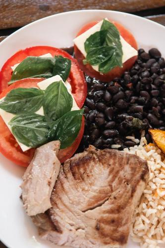a plate of food with tomatoes black beans and meat at Rusteak Living Retreat in natural and peaceful setting in Canafistula in Cañafístula