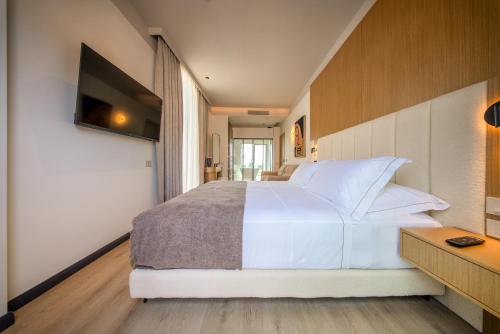 a bedroom with a large white bed and a television at Saint Nicolas Hotel in Himare