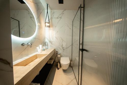 a bathroom with a sink and a toilet and a mirror at Saint Nicolas Hotel in Himare