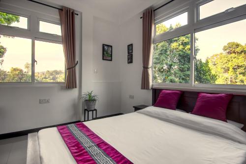 a bedroom with a large bed with two windows at Aquahills in Kandy