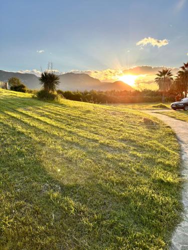 a car parked next to a grass field with the sunset at Beachfront Villa Tranquility in Longós