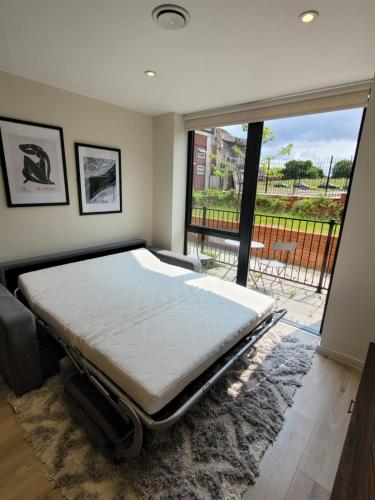 a bed in a room with a large window at Gorgeous GF 2 Bed 2 bathroom Apartment Liverpool 3 in Liverpool