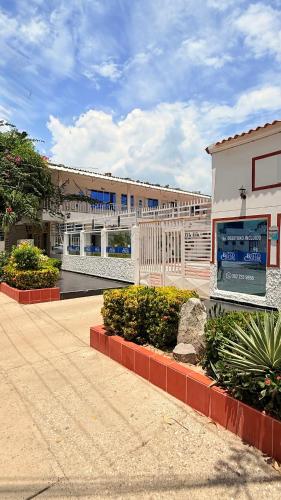 a building with a white fence next to a street at Hotel Bello Caribe Rodadero in Santa Marta