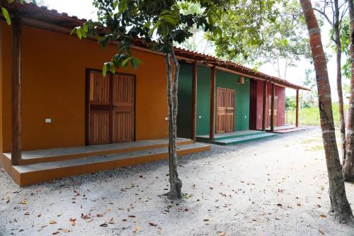 a green and orange building with trees in front of it at Chalés Borborema Cumuru in Prado