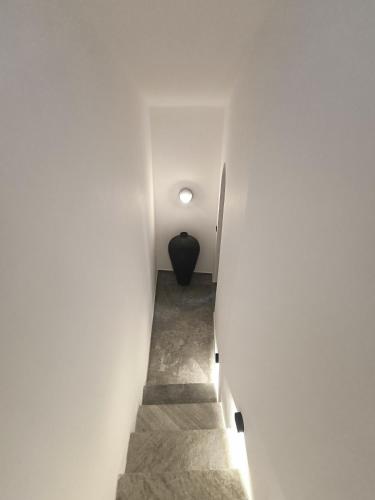 a stairway with a black vase in a white wall at Koniko Santorini Private Pool Villas in Santorini