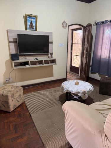 a living room with a flat screen tv and a table at Casa NSA - Nossa Senhora Aparecida in Aparecida