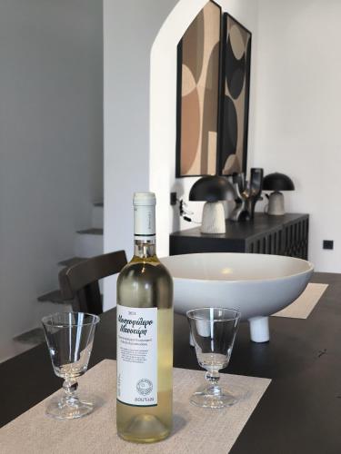 a bottle of wine sitting on a table with two glasses at Koniko Santorini Private Pool Villas in Santorini