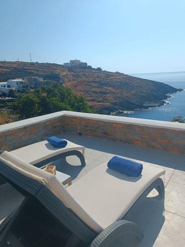 a patio with two lounge chairs and a table on a roof at Iliada Suites Simousi Kythnos in Kithnos