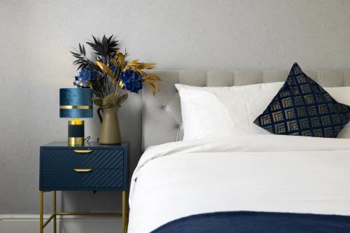 a bedroom with a bed with a blue nightstand with a blue vase at Starboard Stays Southampton in Southampton